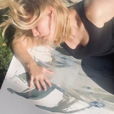 photographic bodyscape - live n°2 Frau mit blonden Haaren liegt auf einer Leinwand und berührt die Farbe.