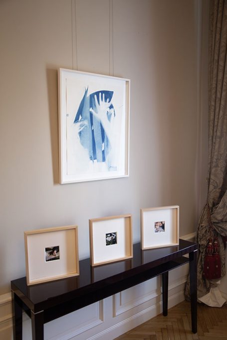 Ein moderner Raum mit einem großen Kunstwerk an der Wand und drei gerahmten Bildern auf einem Tisch.